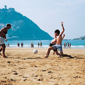 Kursteilnehmer spielen Fußball am Strand